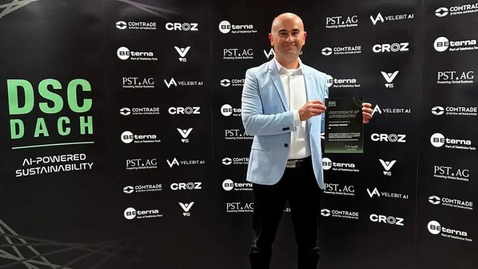 A man holding a certificate in front of a DSC DACH event backdrop.