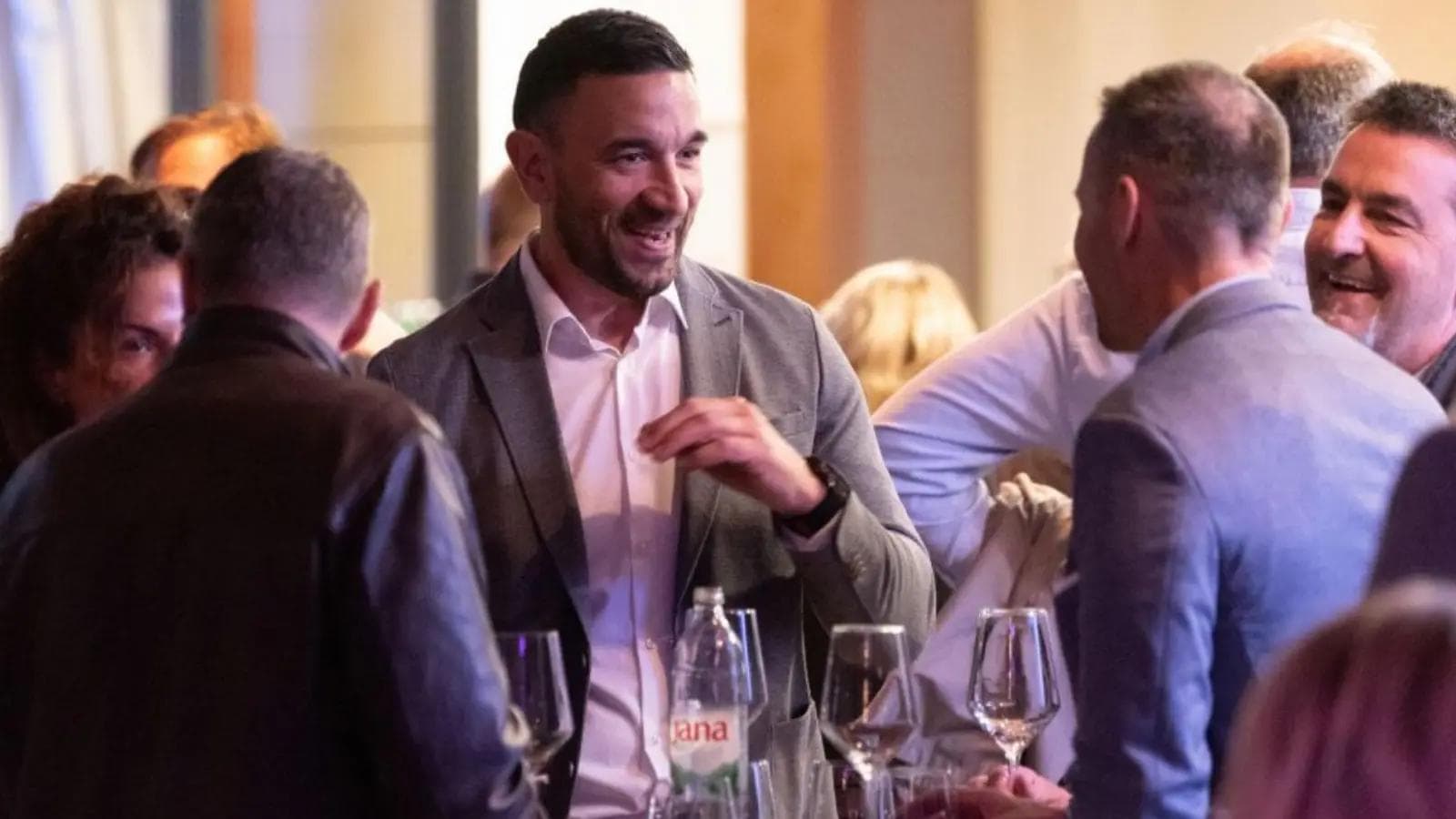 People mingling at a conference afterparty at a table.