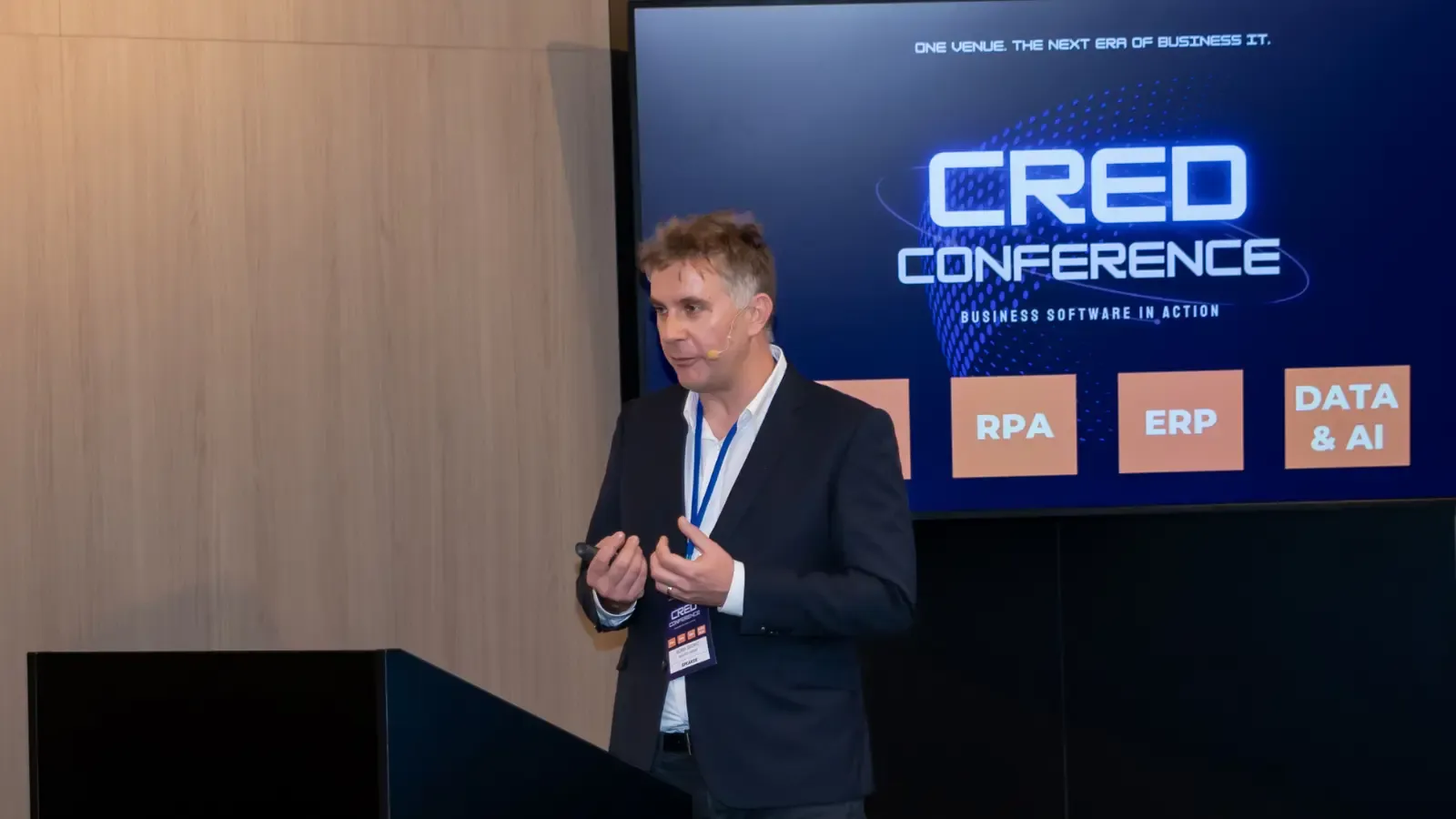 Speaker presenting at CRED Conference 2025 beside RPA, ERP, Data & AI screen.